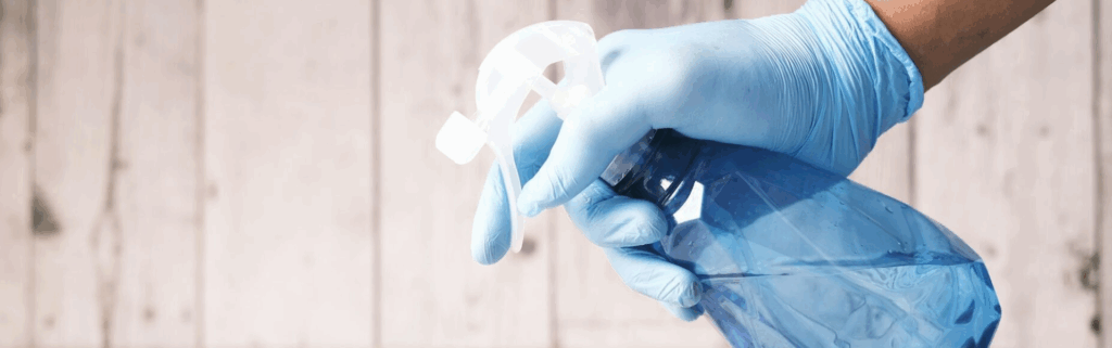 Persona con guantes sosteniendo un pulverizador de limpieza